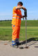 Photo of an employee in orange overalls at the edge of a gravel road next to a green meadow, showing how EBG can be replaced without trenching.